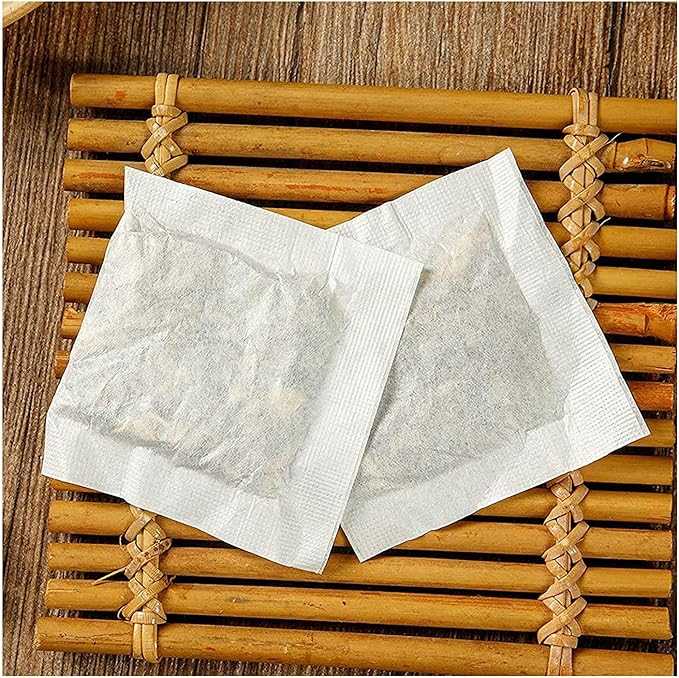 Two white tea bags on a wooden surface